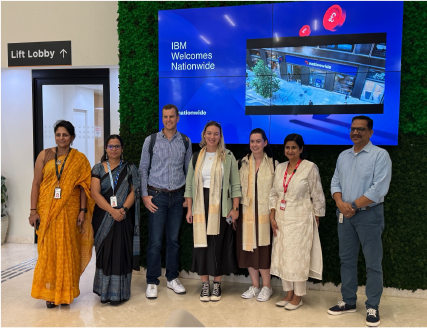 Team standing in front of an IBM Welcomes Nationwide screen